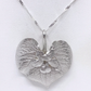 A silver heart-shaped pendant necklace with a textured, leaf-like surface and a small central floral detail, suspended from a twisted silver chain against a white background.
