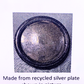 A round silver-coloured metal plate with a textured, recycled finish and a decorative beaded rim, shown on a patterned background with text below reading 'Made from recycled silver plate shown in picture'.