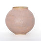 A round ceramic vessel. Glaze is pale pink, with a bubbly texture. 