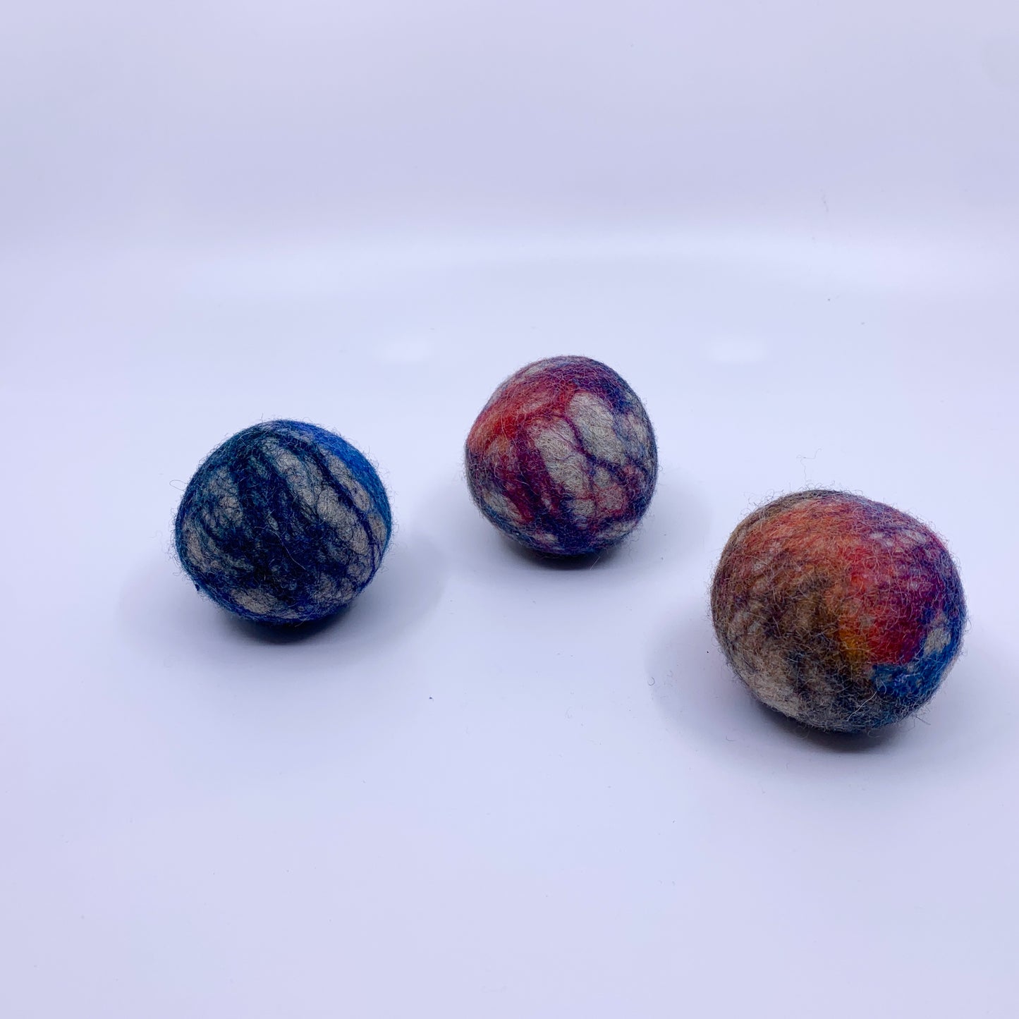 Three multicoloured felt balls on a white background