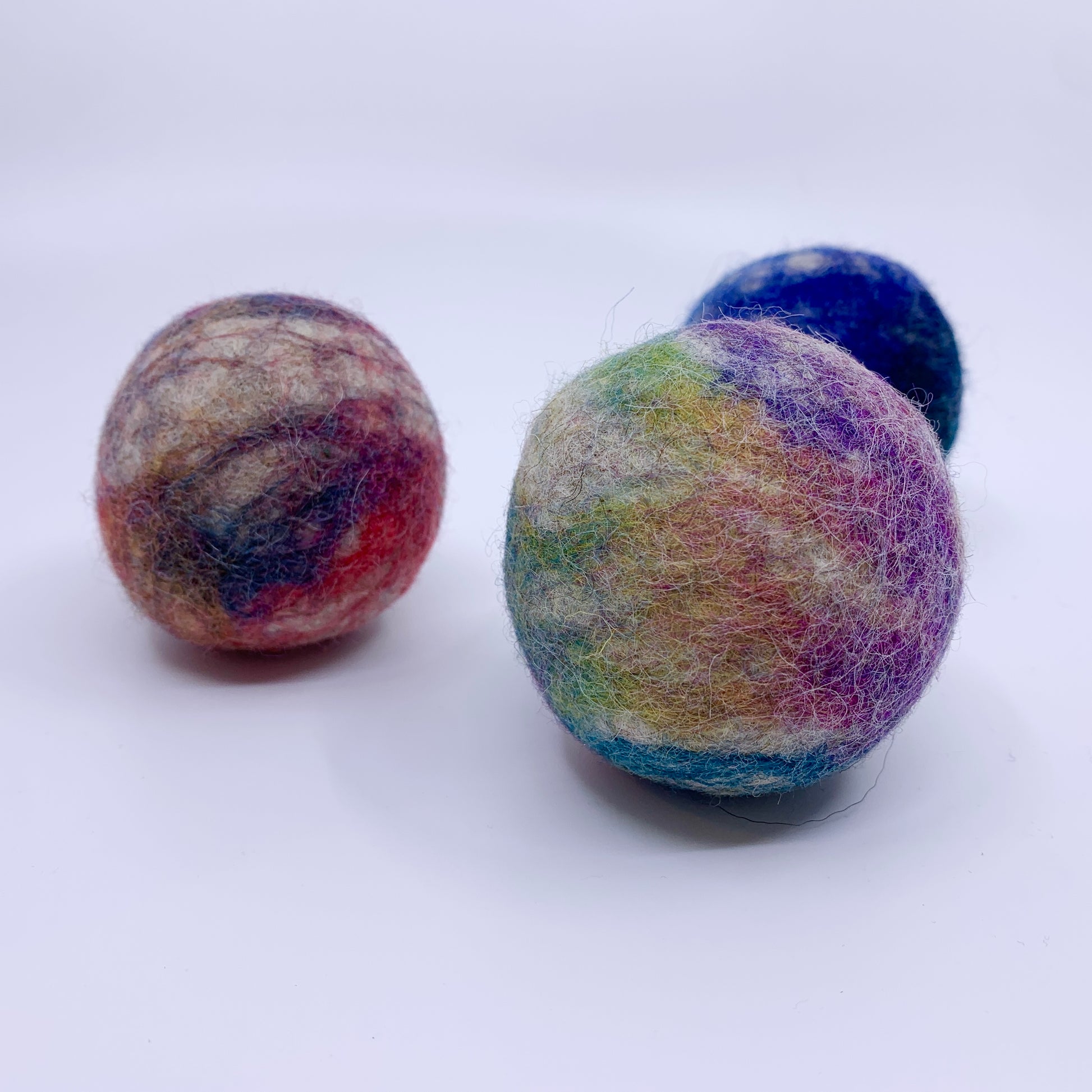 Three multicolored felted balls on a white background