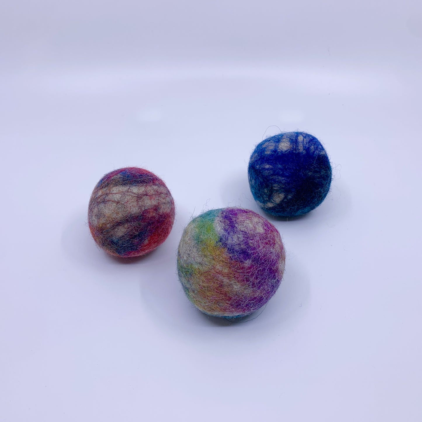 Three multicolored felt balls on a white background