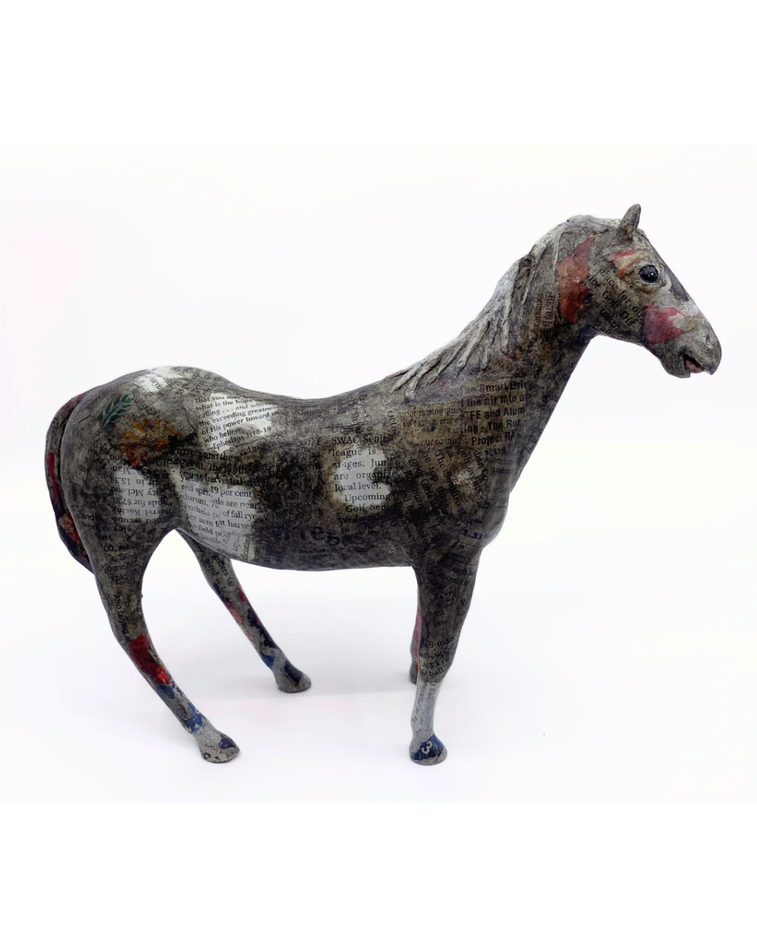 A small decorative horse figurine with a distressed, textured finish in dark gray, black, and white, accented with red and blue paint on its legs and face, set against a plain white background.