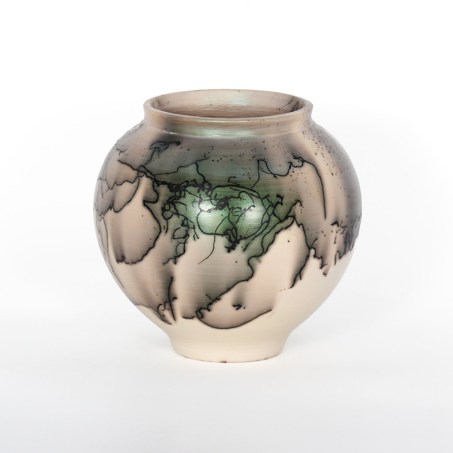 A round ceramic vessel. The clay is beige, with black lines from burnt horsehair, and green and grey spots of glaze.