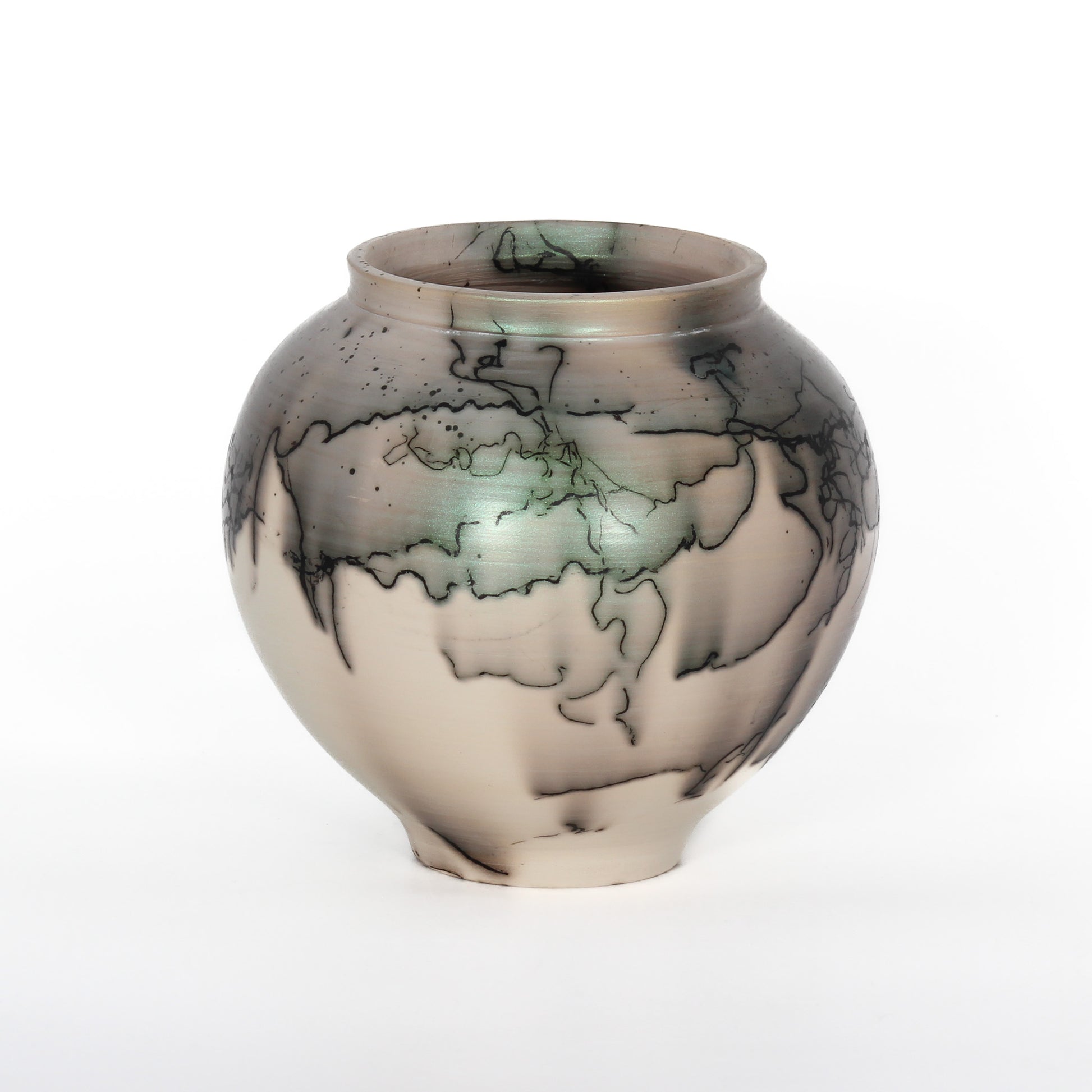 A round ceramic vessel. The clay is beige, with black lines from burnt horsehair, and green and grey spots of glaze.