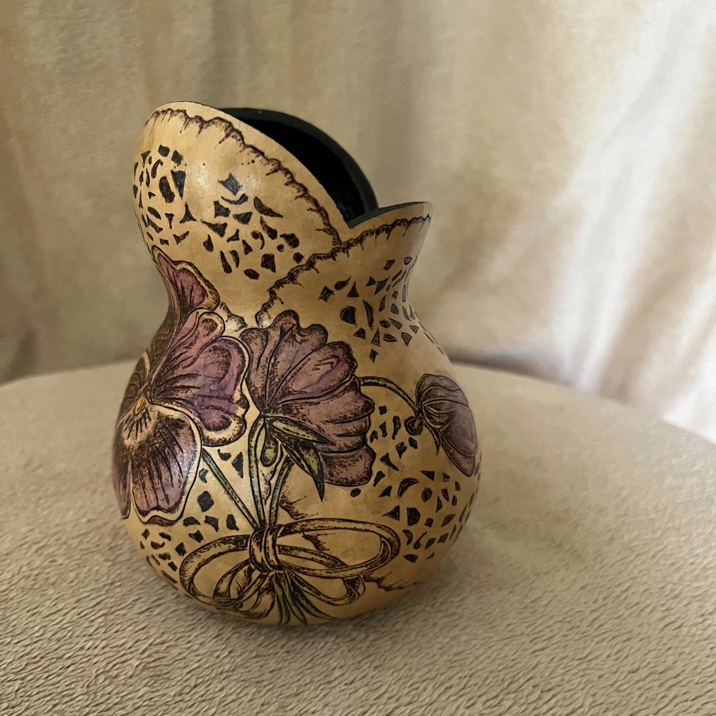 Decorative gourd with floral patterns on a beige surface