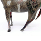 A sculptural horse figurine decorated with collage elements, including newspaper print, text, and small printed images, shown against a plain white background.