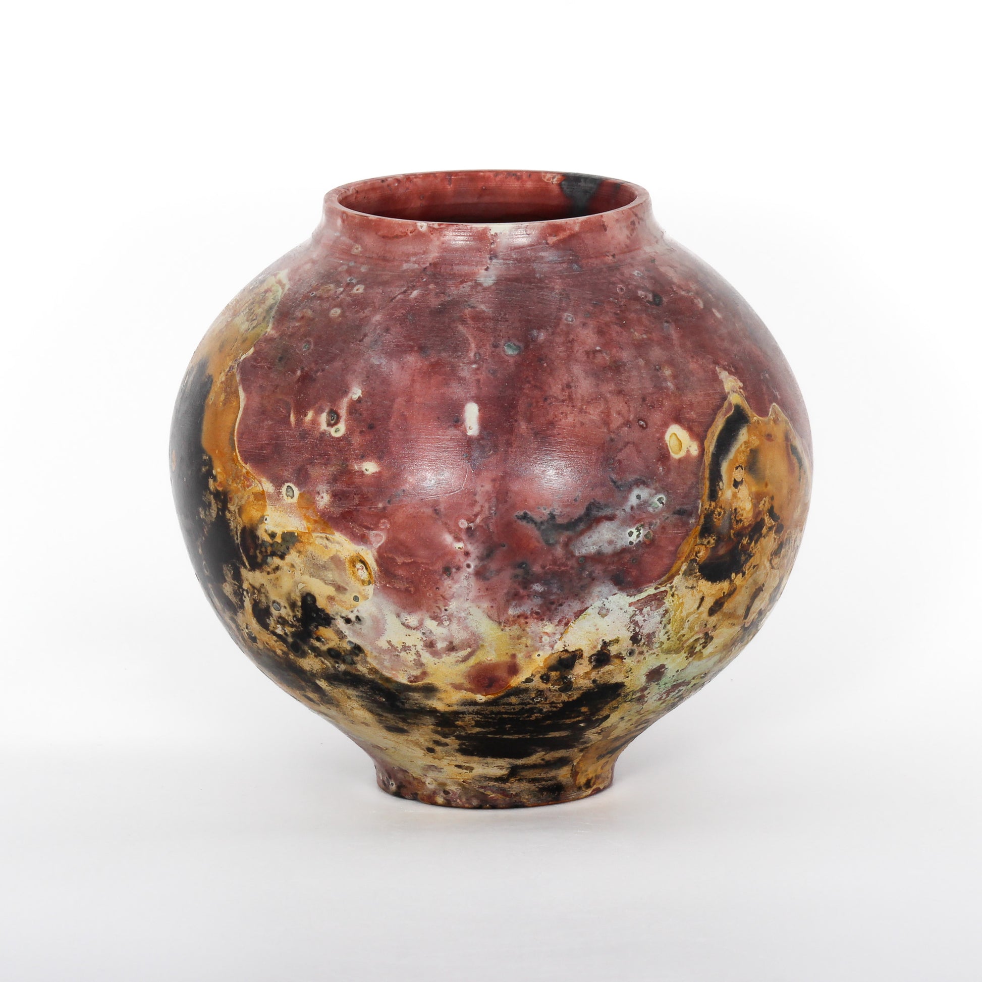 A round ceramic vessel. Surface is rust, brown, orange, black, and beige.