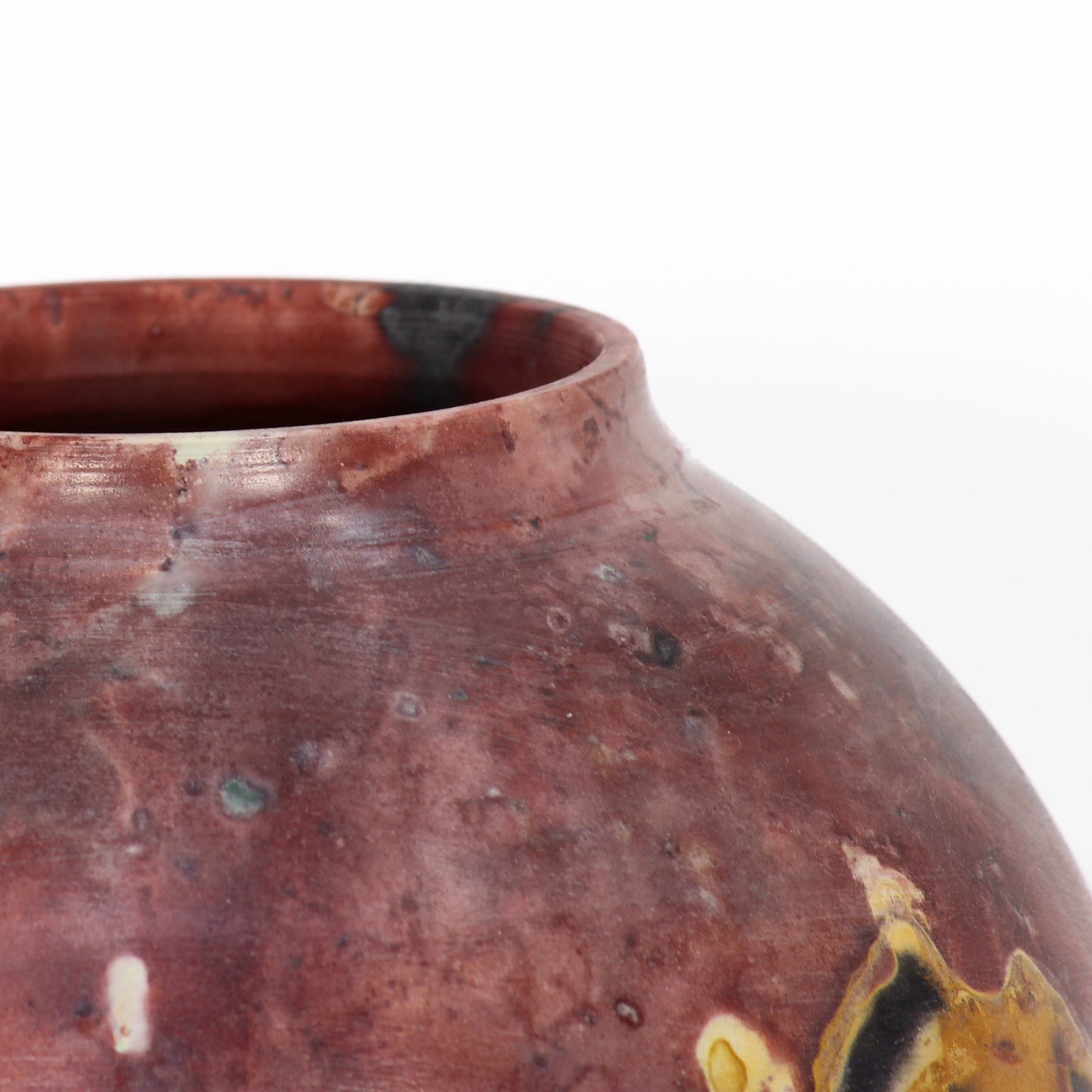 A round ceramic vessel. Surface is rust, brown, orange, black, and beige.