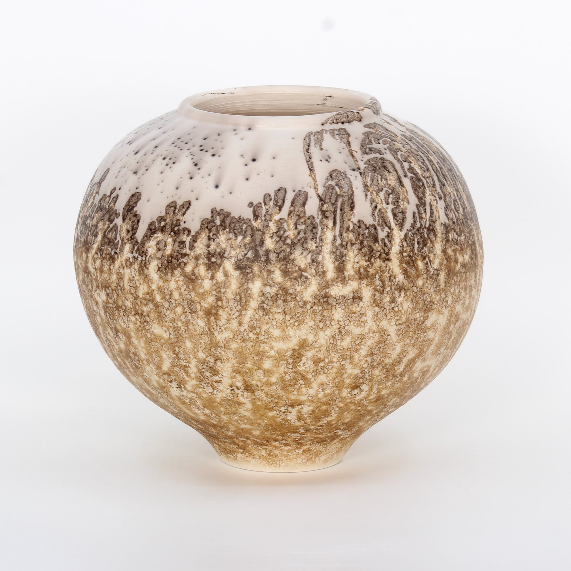 A round ceramic vessel. Surface is textured, with beige, tan, and brown crackly splotches.