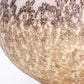 A round ceramic vessel. Surface is textured, with beige, tan, and brown crackly splotches.