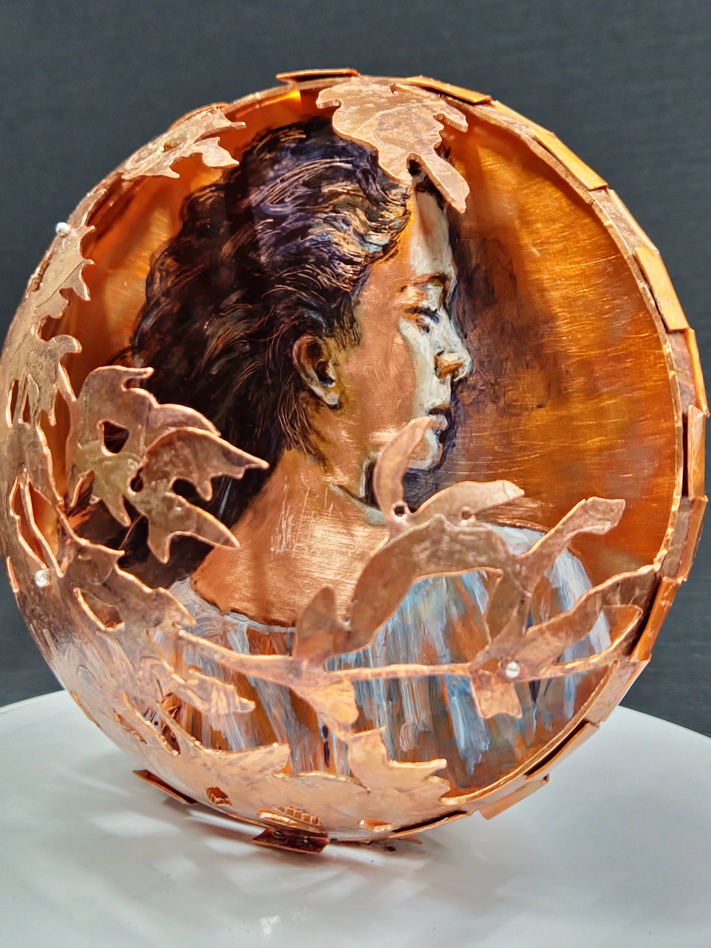 Decorative copper bowl with leaf patterns on a dark background