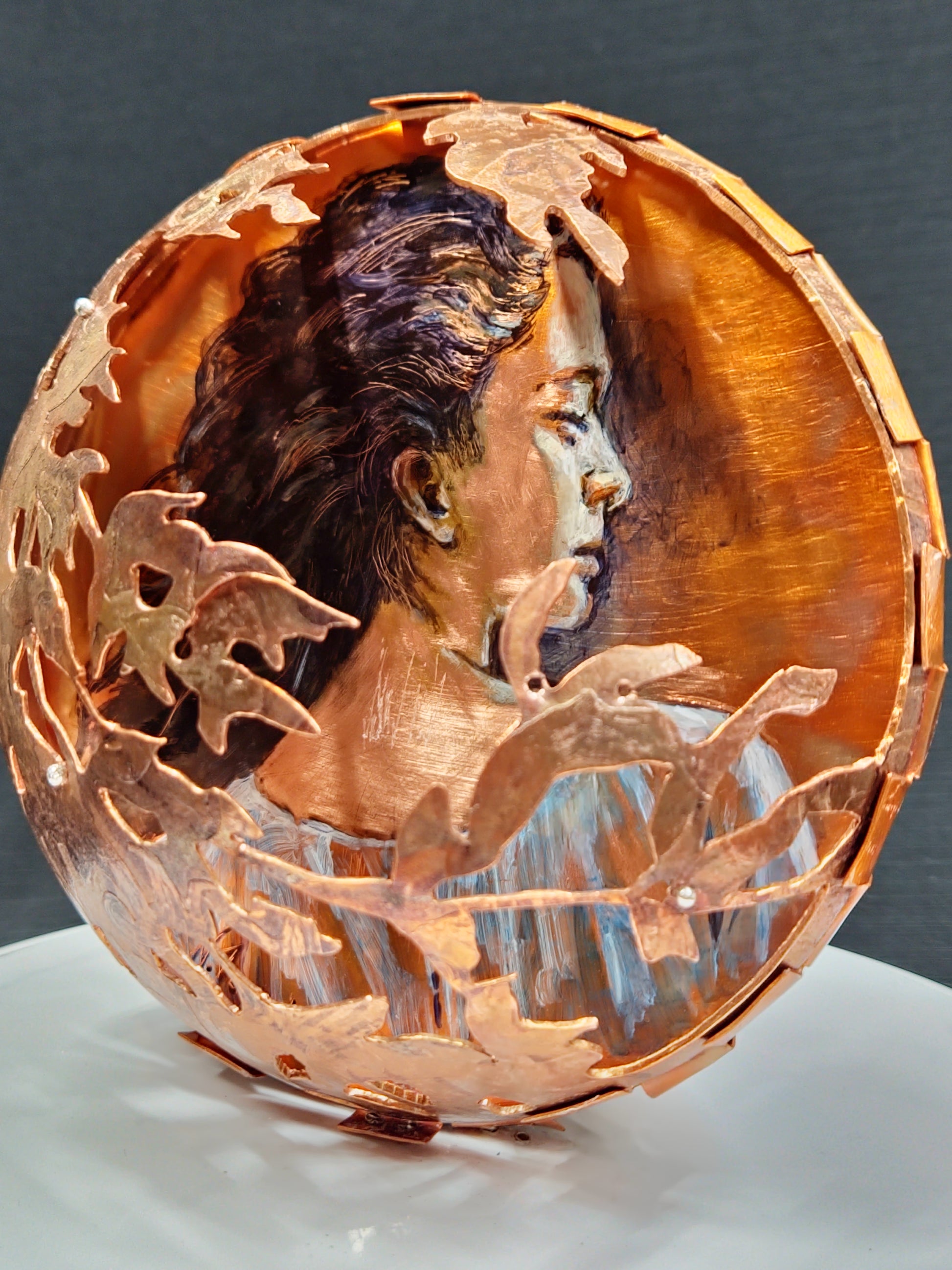 Decorative copper bowl with leaf patterns on a dark background
