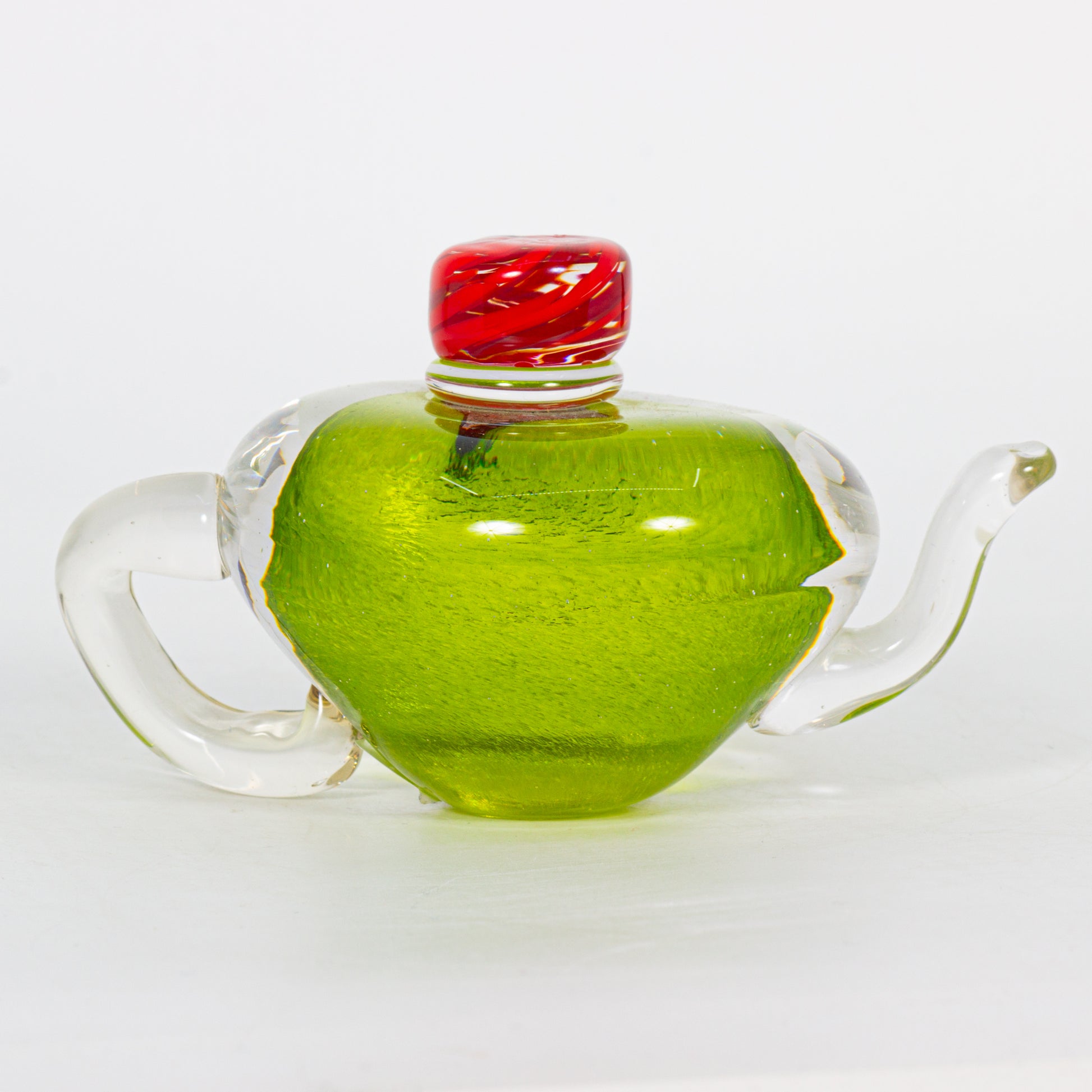 Clear glass teapot decoration with a red lid on a white background