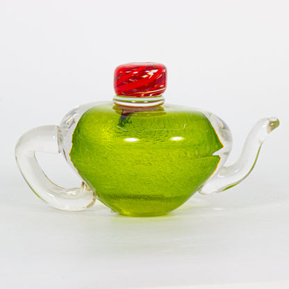 Clear glass teapot decoration with a red lid on a white background