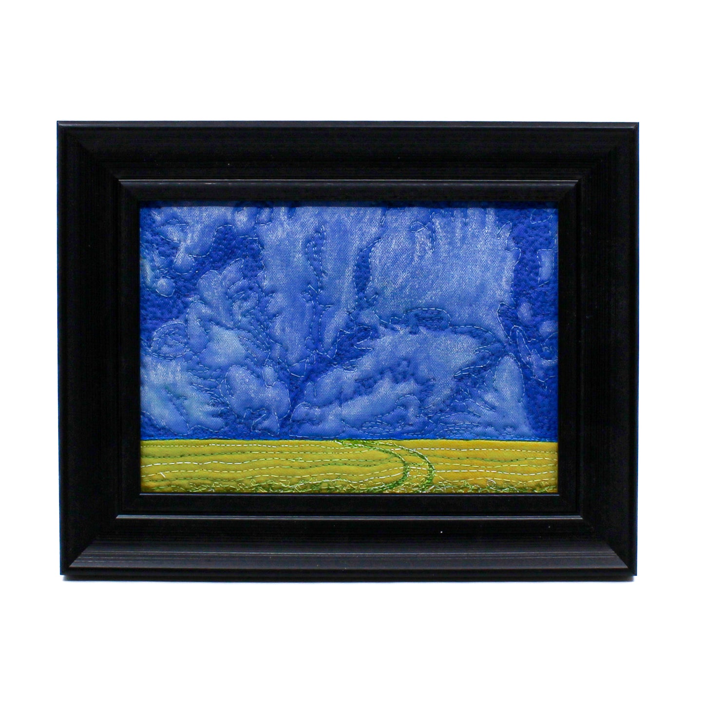 Thread painting of a blue sky over a yellow canola field with a road 