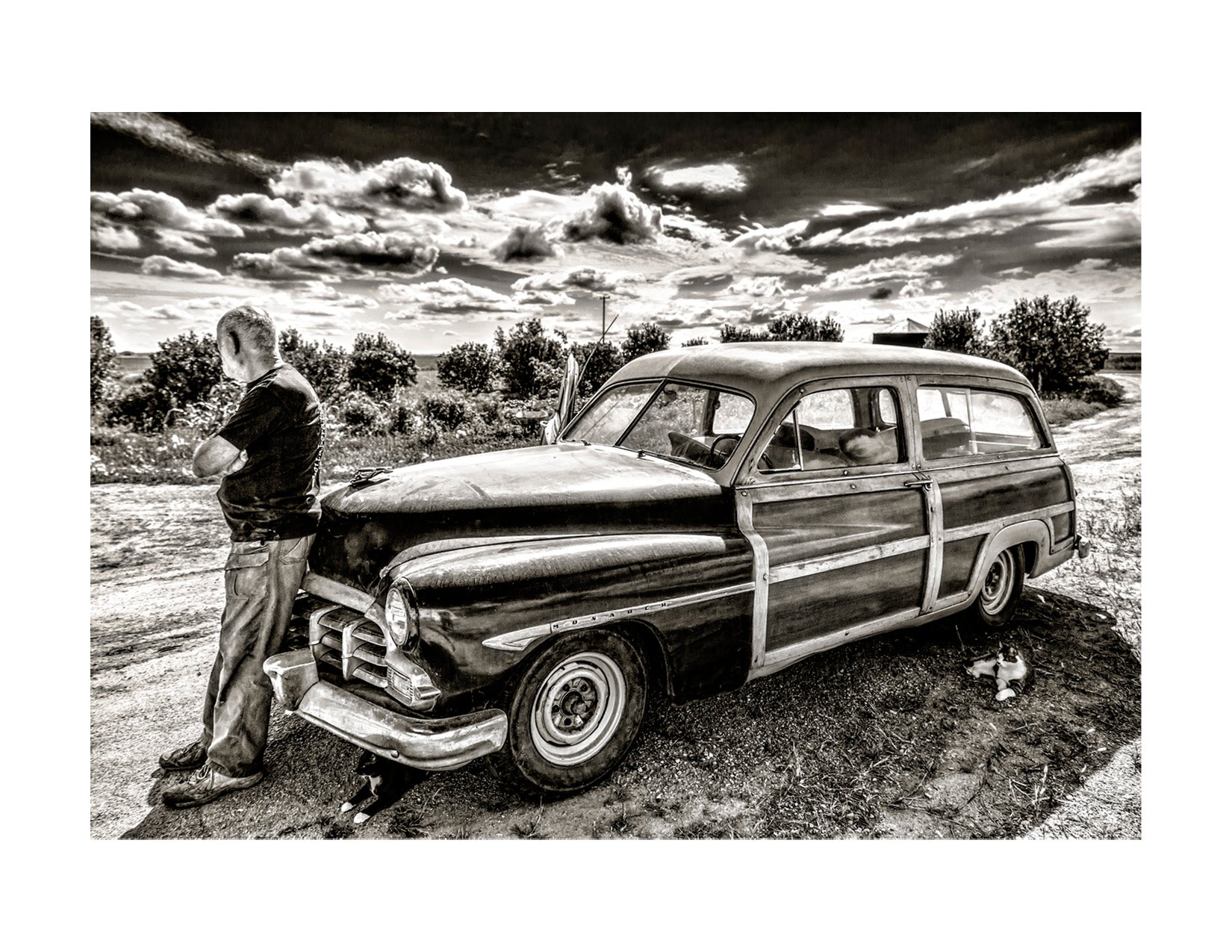 Black and white photo of a man and vintage car