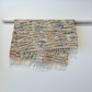 Colourful woven rug with fringe hanging over a bar