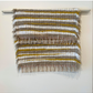 Brown, white and mustard woven fringe rug hanging over a bar