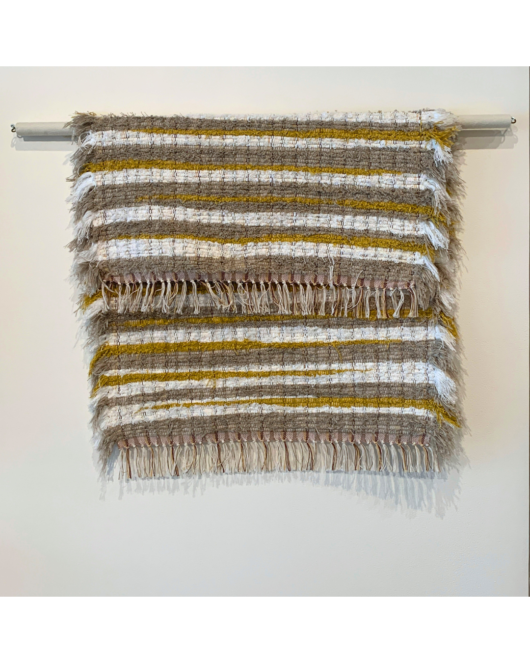 Brown, white and mustard woven fringe rug hanging over a bar