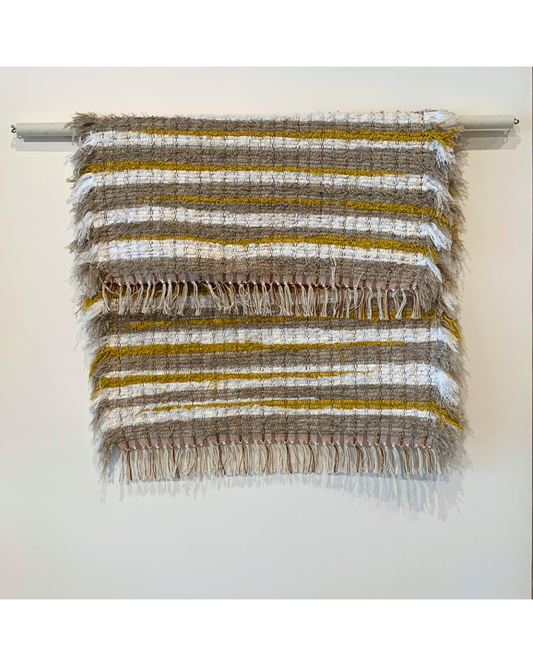 Brown, white and mustard woven fringe rug hanging over a bar