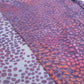 Scarf with a pattern of pink and purple rounded shapes on a plain background.