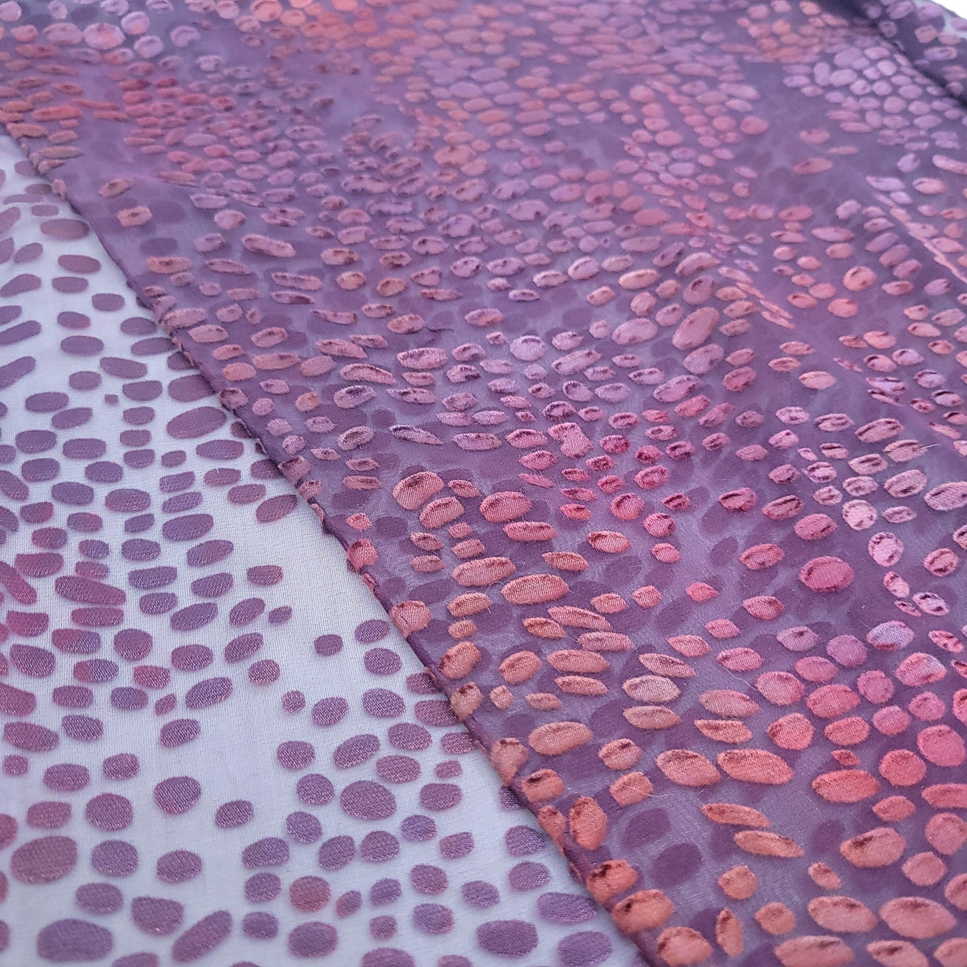 Scarf with a pattern of pink and purple rounded shapes on a plain background.