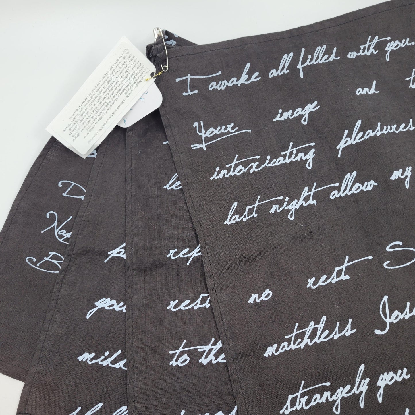 Textile with white cursive text on a dark fabric background