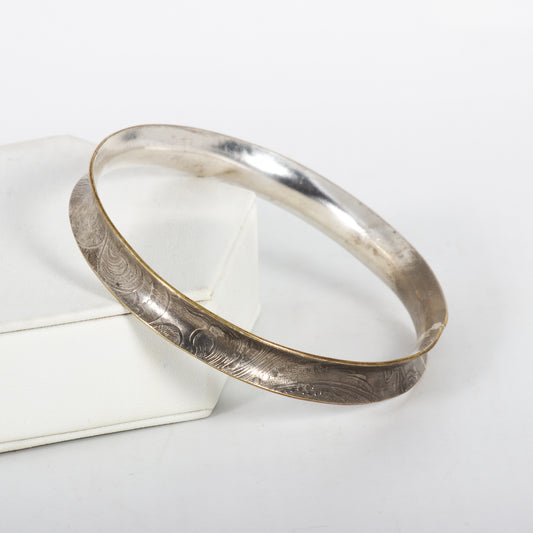 Silver bracelet with engraved design on a white surface