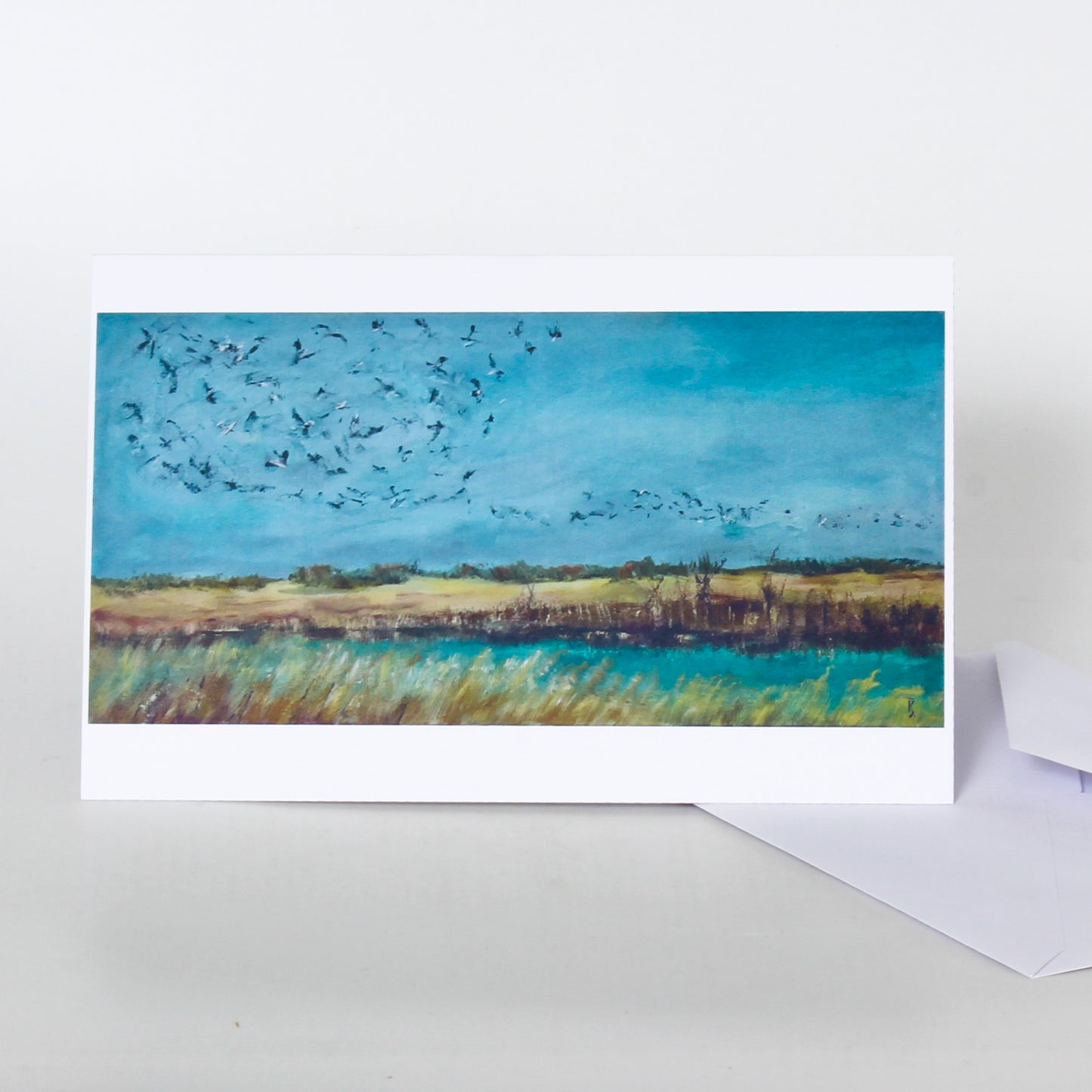 Greeting card with a painting of birds flying over a landscape on a white background