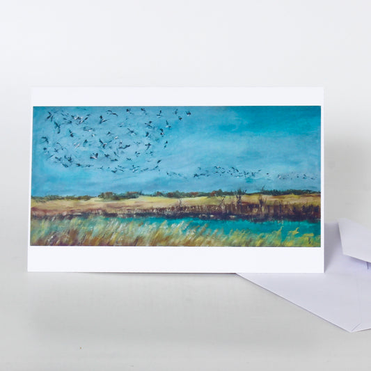 Greeting card with a painting of birds flying over a landscape on a white background