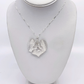 A silver pendant necklace featuring a textured, leaf-like heart design with a small flower in the center, displayed on a white jewelry bust.