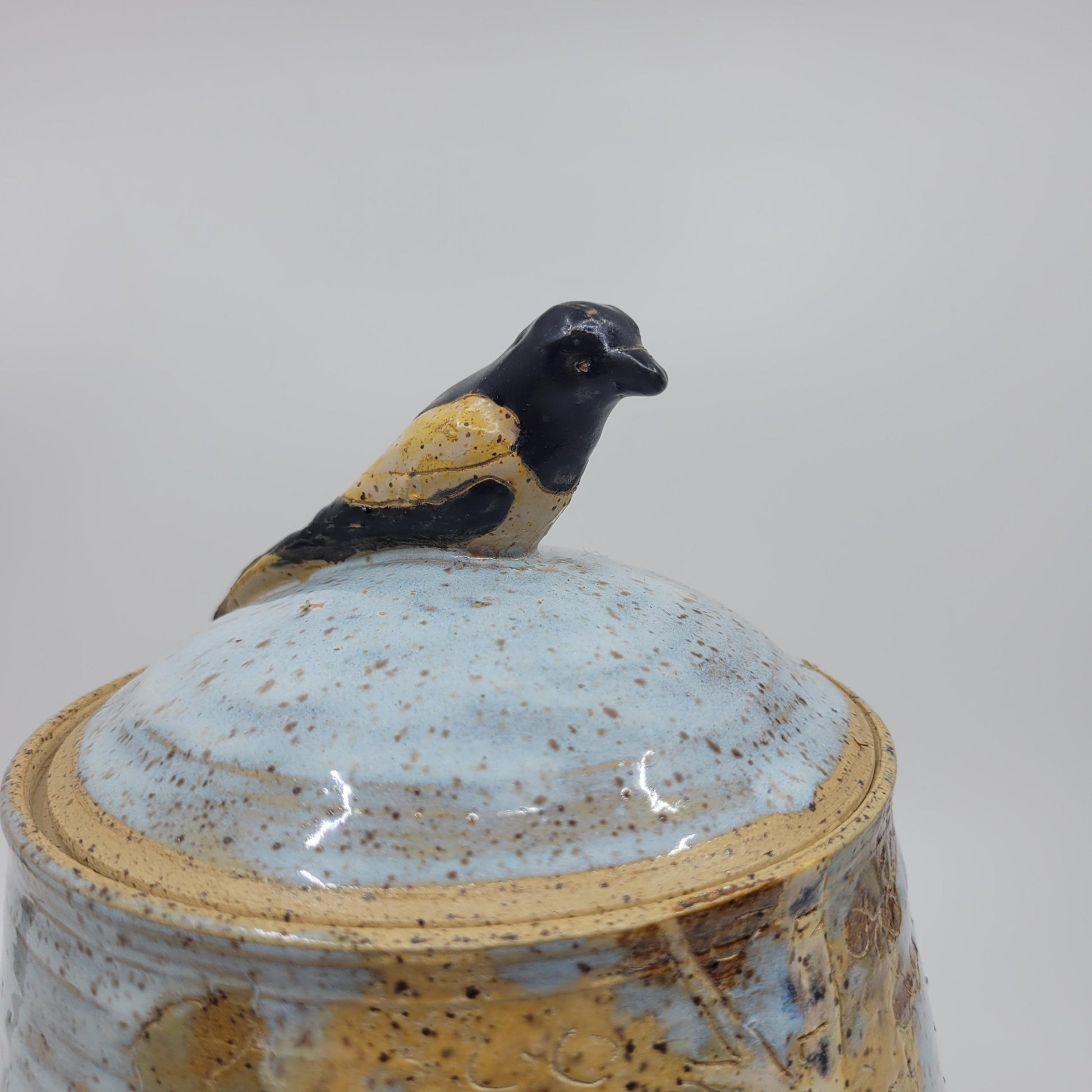 Ceramic jar with a bird lid on a white background