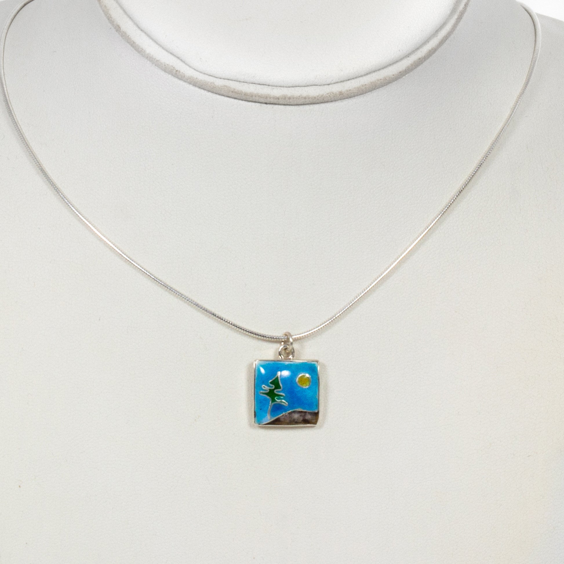Necklace with a square pendant featuring a nature scene on a white background