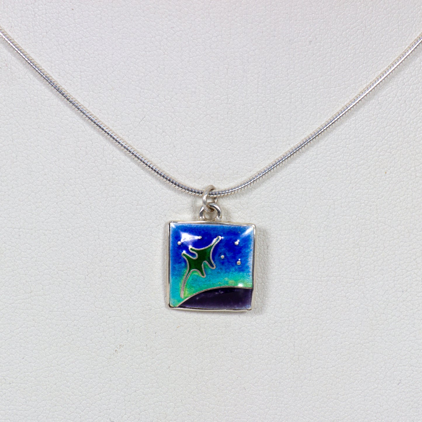 Necklace with a square pendant featuring a green star design on a light gray background