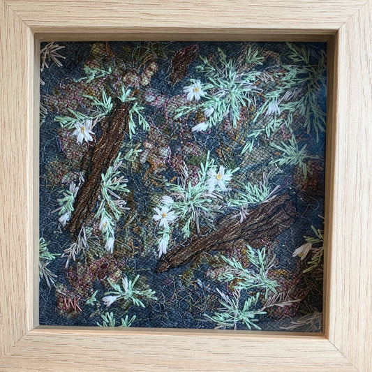 Framed artwork of green embroidered plants and flowers