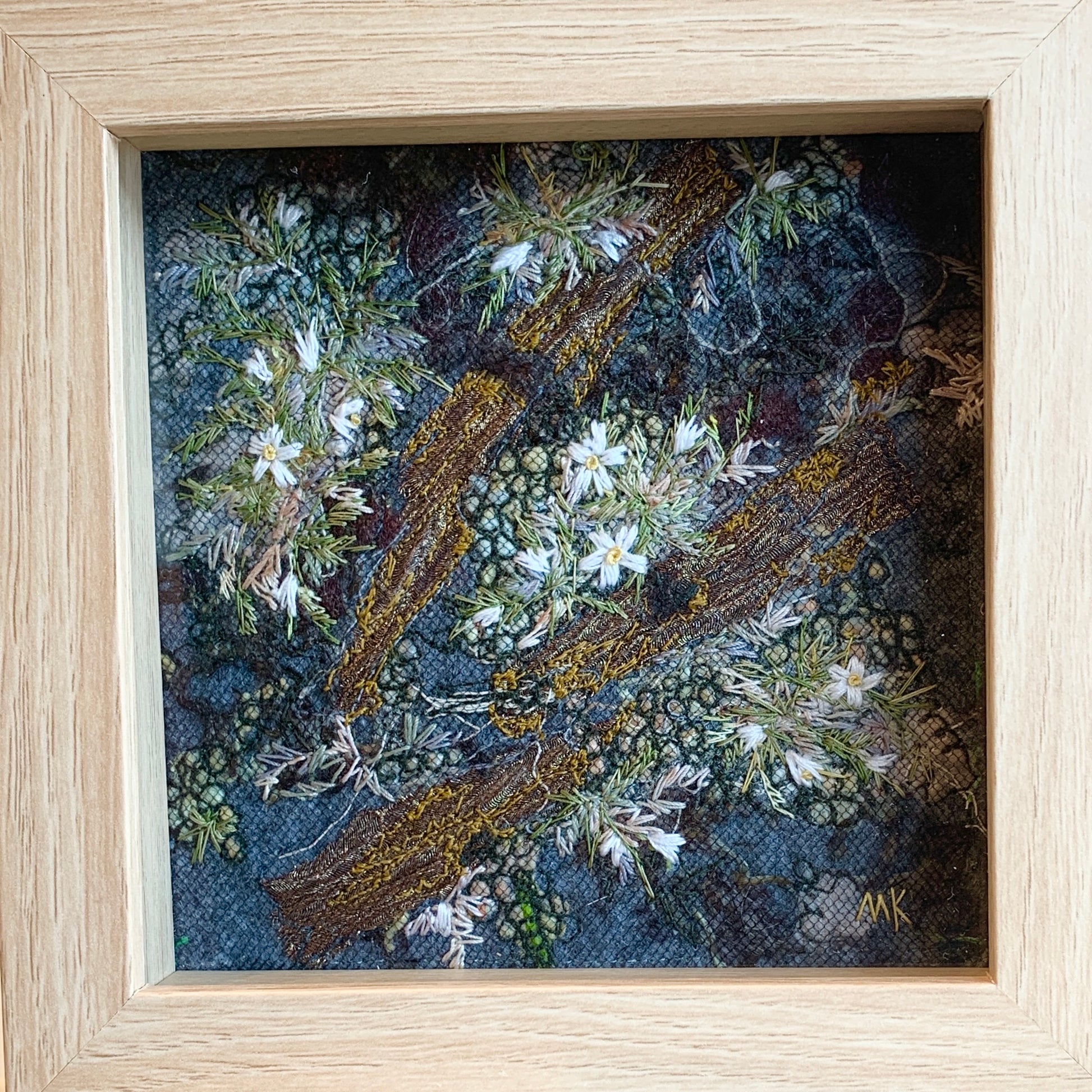 Framed artwork of embroidered flowers and wood 