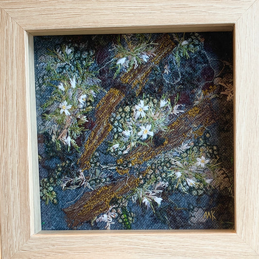 Framed artwork of embroidered flowers and wood 