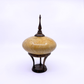 A decorative lidded object with a rounded wood body in warm beige and yellow marbled tones, mounted on a dark brown wooden stand with a pointed finial lid, photographed against a plain white background.