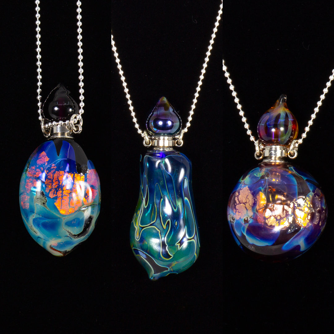 Three colorful glass pendants on chains against a black background