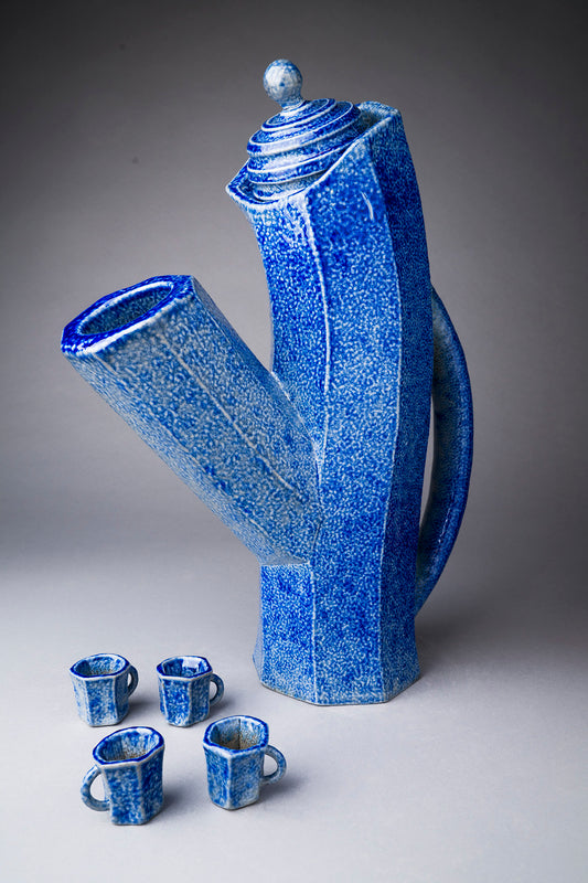Blue ceramic teapot and cups on a gray background
