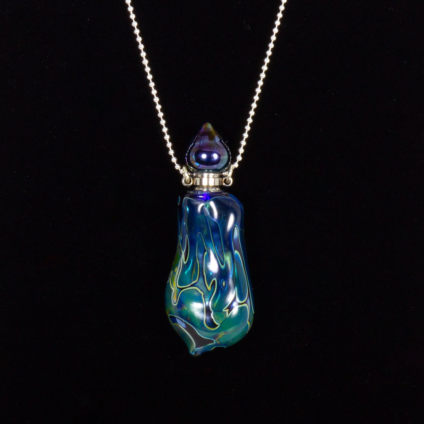Glass pendant necklace with blue and green design on a black background