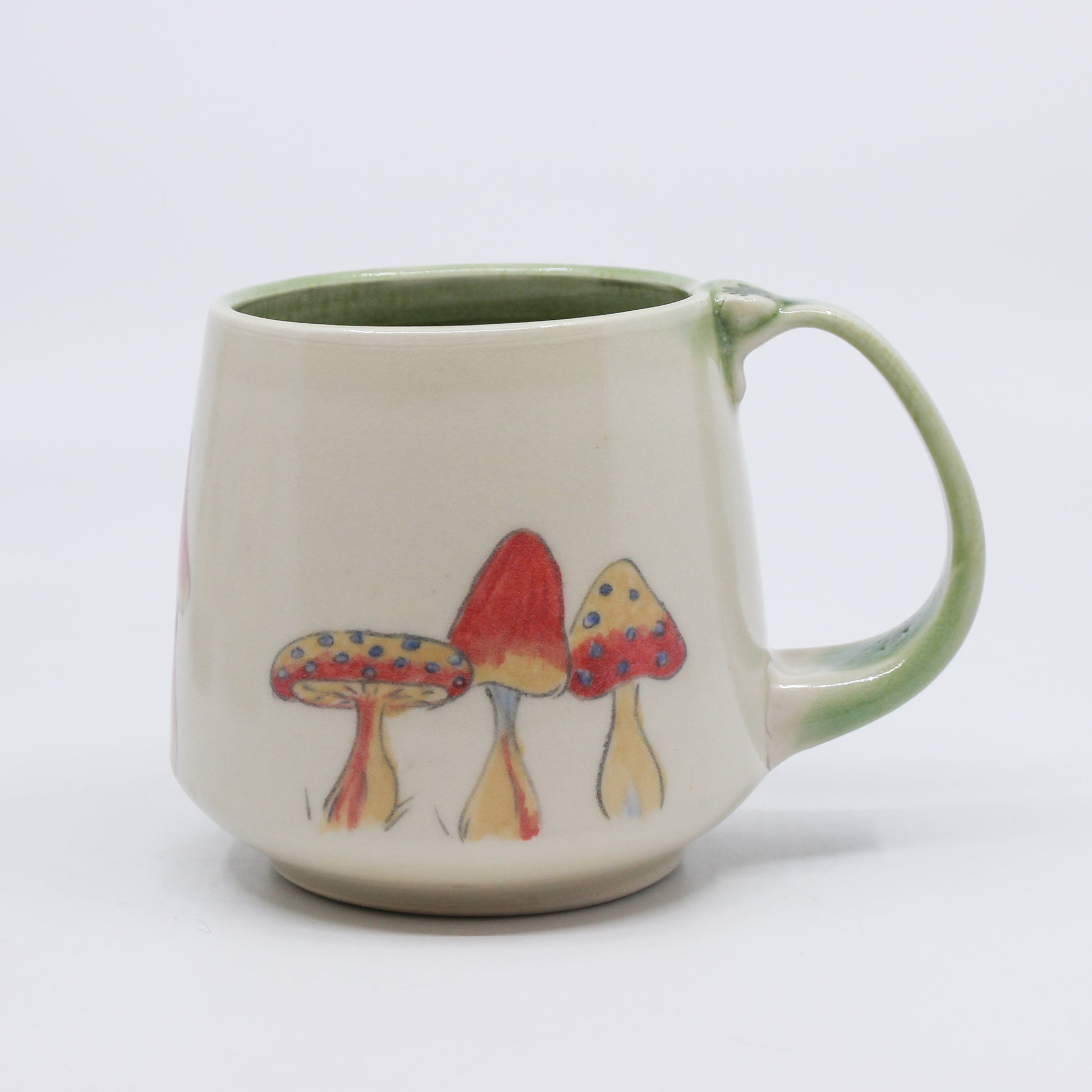 Hand-painted mushrooms on white and green mug