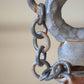 Detail of clay sculpture with chain on a gray background