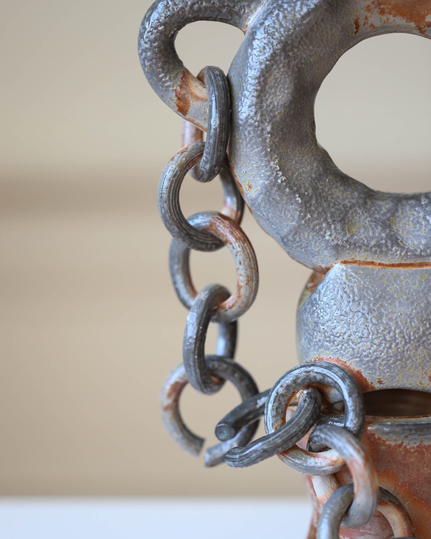 Detail of clay sculpture with chain on a gray background