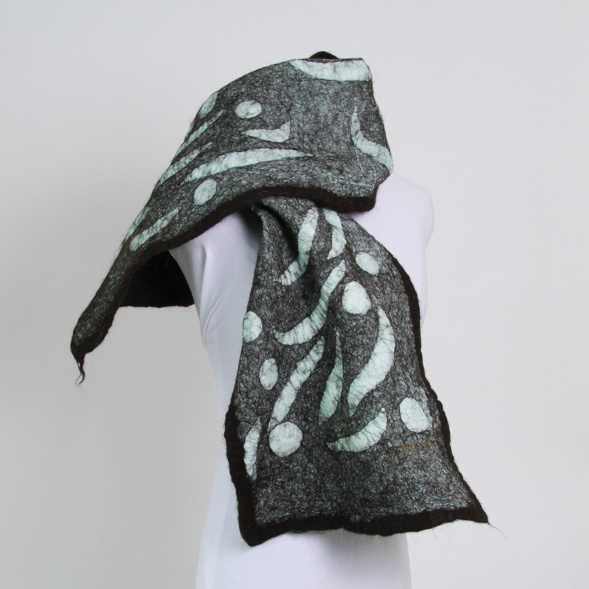 Teal scarf with abstract shapes trimmed with dark brown. 