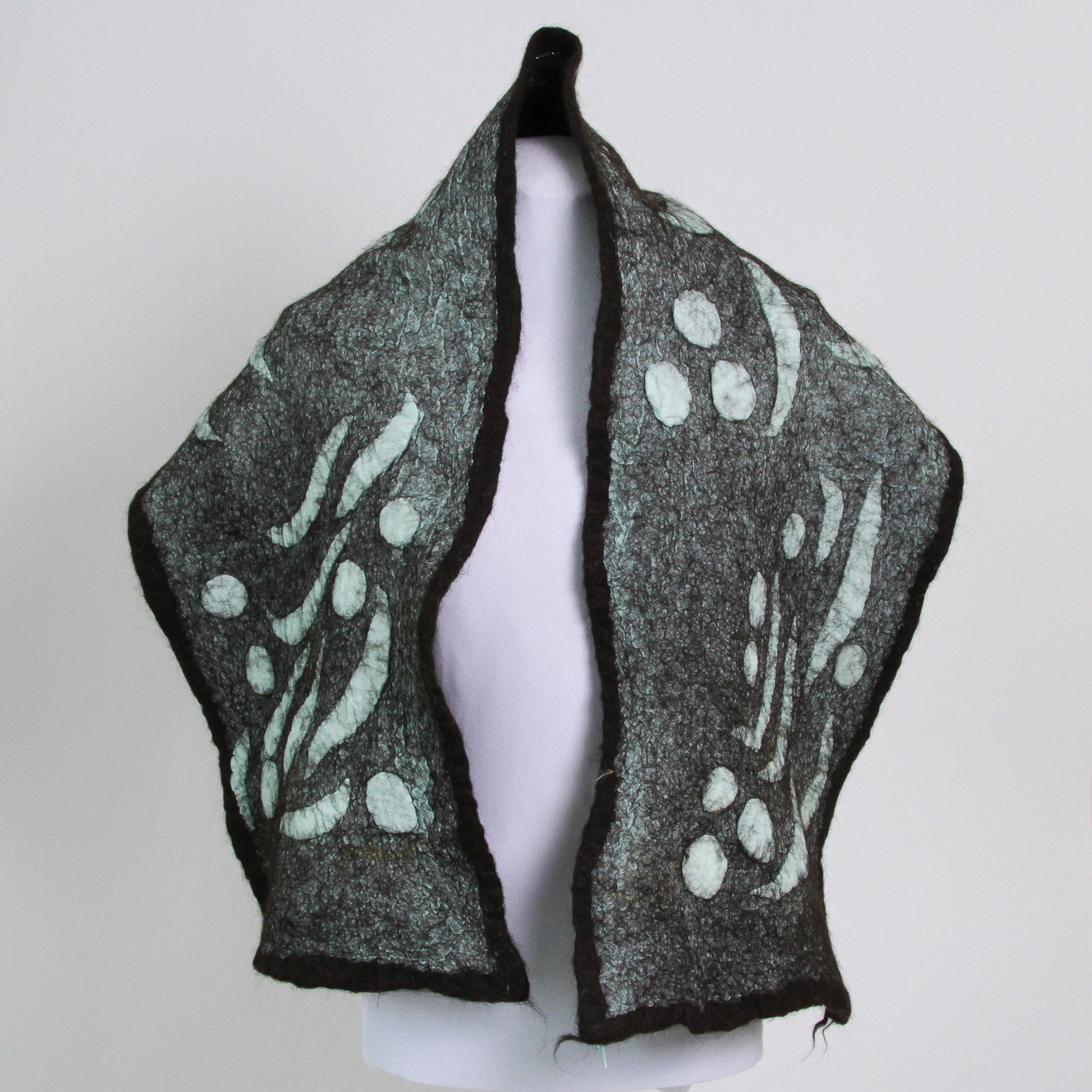 Teal scarf with abstract shapes trimmed with dark brown. 