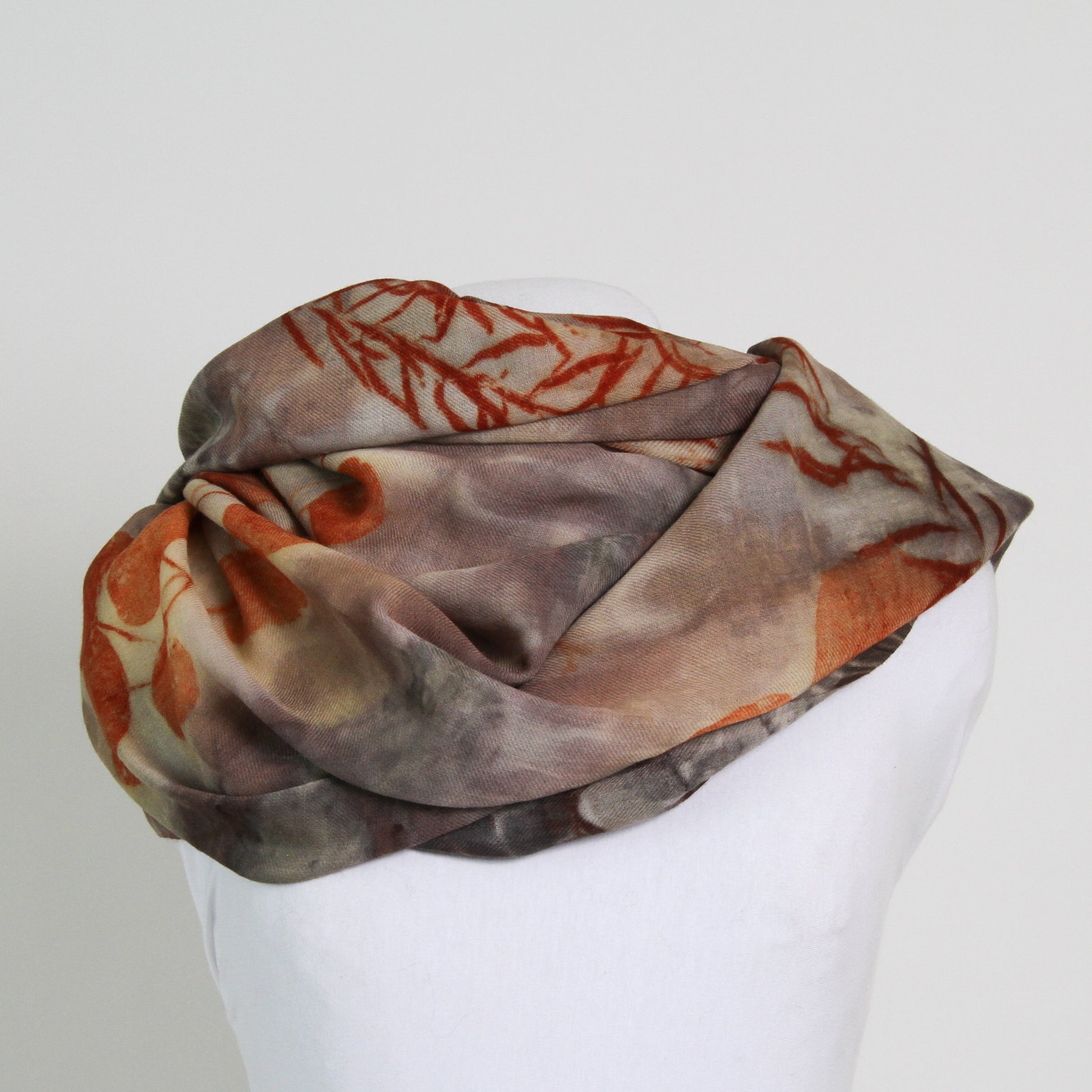 Back view of brown wool scarf with orange printed leaves and foliage