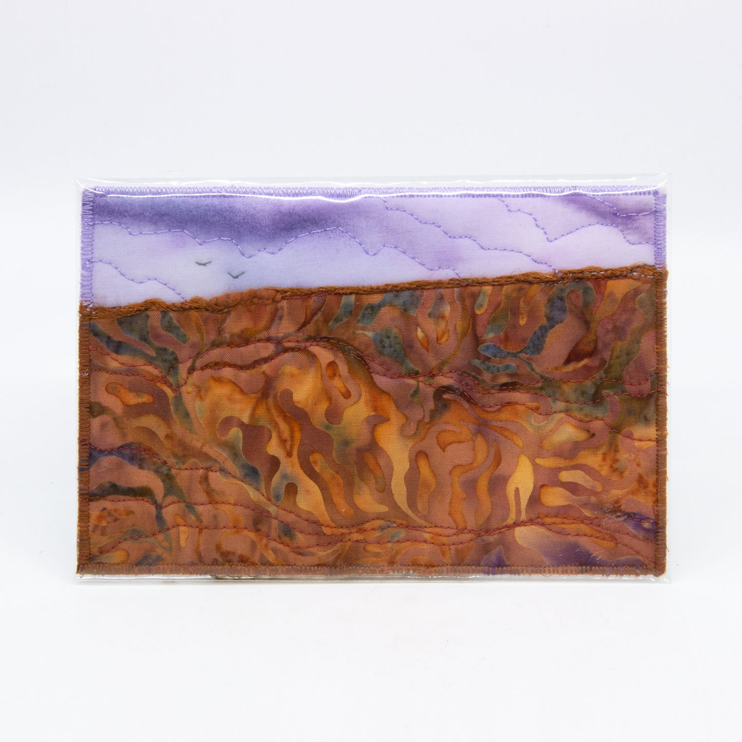 Mini art quilt of a prairie: purple sky with birds,  brown fields with dyed patterns 