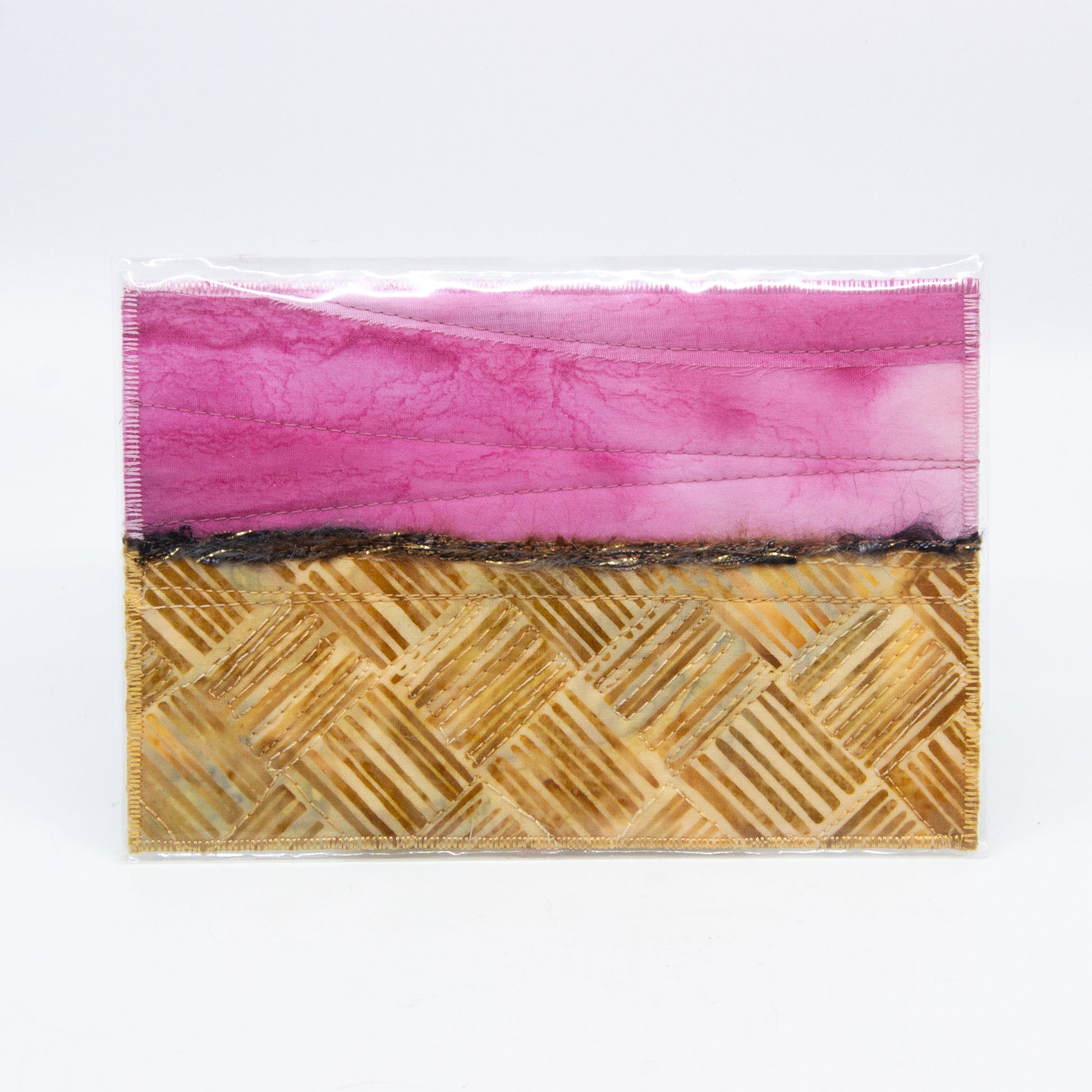 Mini art quilt of a prairie: pink sky and brown hatched fields 